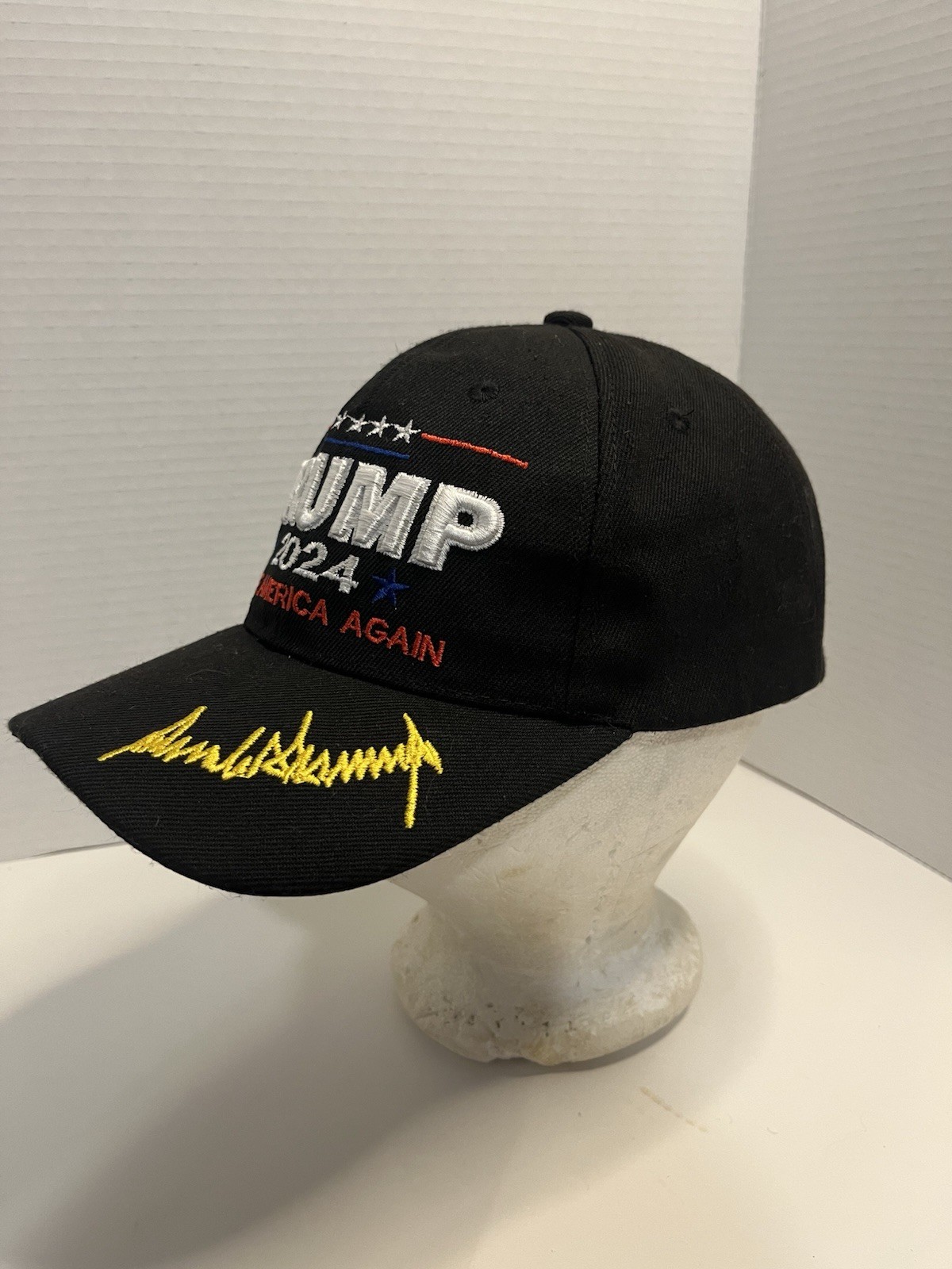 This is a black TRUMP 2024 SAVE AMERICA AGAIN text and a golden-yellow signature